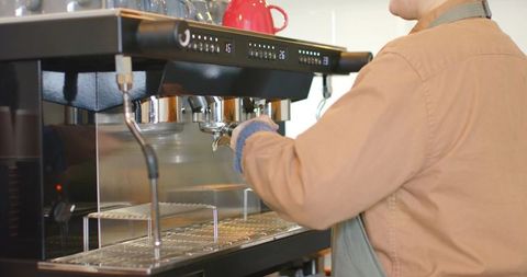Female barista preparing espresso using professional commercial espresso machine in cafe