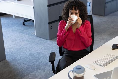 Professional woman in office drinking coffee at desk
