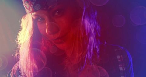 Moody neon portrait of woman wearing bandana and plaid shirt with color gels and bokeh