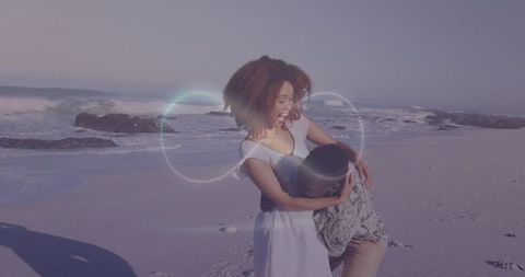 Romantic seaside embrace with laughing couple holding each other on sandy shore