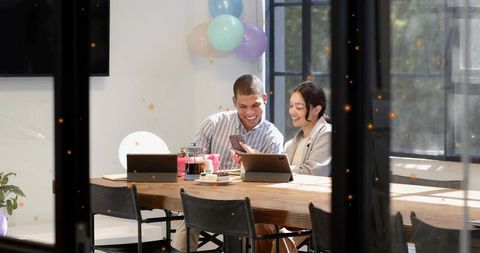 Young professionals collaborating over smartphone and laptops in modern pastel office