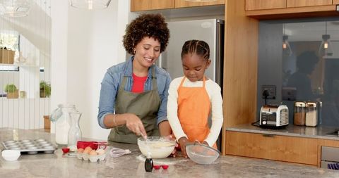Diverse Mother and Daughter Enjoy Baking Together in Modern Kitchen