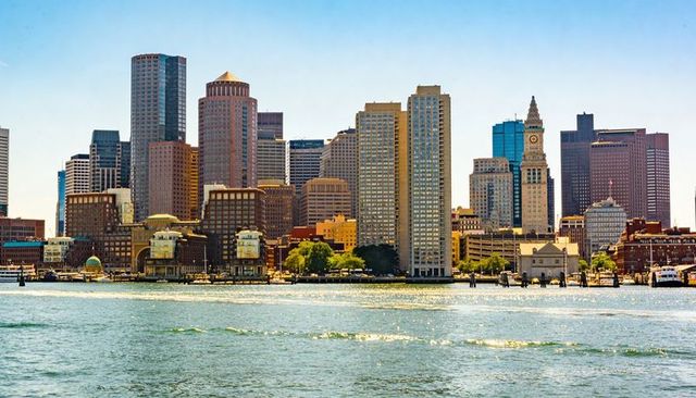 Boston waterfront skyline featuring iconic clock tower and harbor reflections