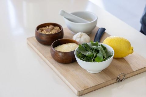 Preparing pesto ingredients on cutting board with basil parmesan pine nuts garlic lemon