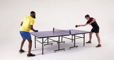 Two friends competing in indoor table tennis match