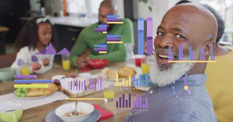 Smiling senior man turning to camera at family breakfast with colorful data visualization