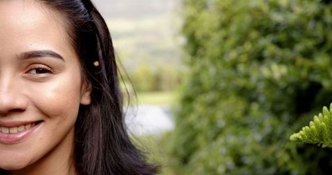 Half-Face of Smiling Young Woman with Nature in Background