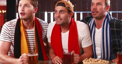 Excited Friends Watching Sports Game in Bar Setting