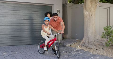 Father Teaching Daughter to Ride Bicycle While Mother Smiles Supportively