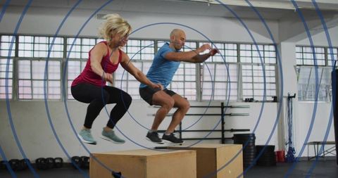 Partners performing synchronized box jumps for plyometrics, explosive strength and teamwork