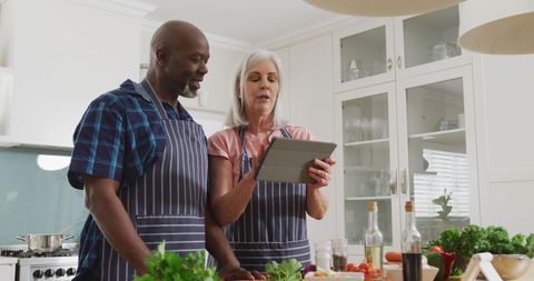 Senior Couple in Aprons Cooking Together in Modern Kitchen