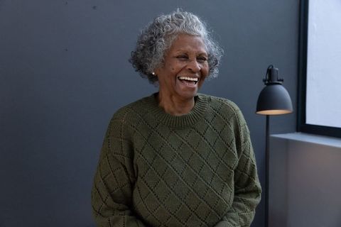 Elderly woman laughing indoors radiating joy and warmth
