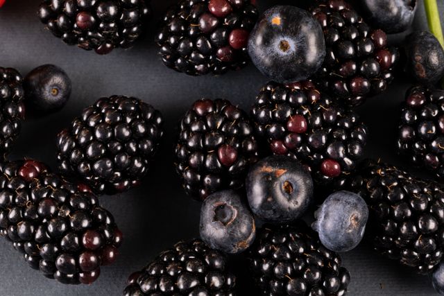 This image shows a close-up of fresh blackberries and blueberries, highlighting their natural texture and color. Ideal for use in articles or advertisements about healthy eating, organic food, nutrition, and diet. Perfect for food blogs, recipe websites, and health magazines.