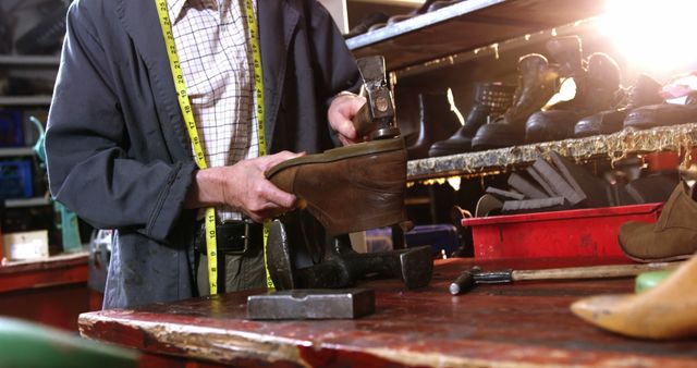 Cobbler repairing brown boot in workshop, using various tools and equipment. Perfect for illustrating traditional craftsmanship, leatherworking professions, and manual repair services. Could be used in articles about artisanal trades, vocational training, or DIY shoe repair tutorials.