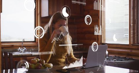 Woman Analyzing Financial Data on Laptop in Kitchen