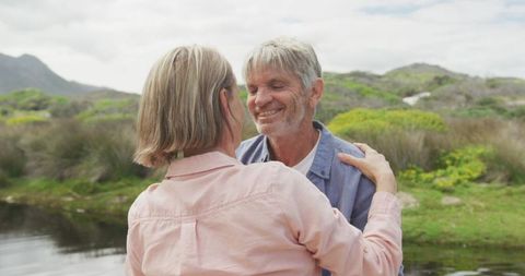 Senior Couple Embracing by Scenic Riverside Outdoors