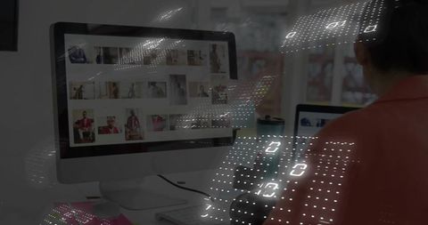 Asian editor selecting portrait thumbnails on desktop with futuristic data overlay