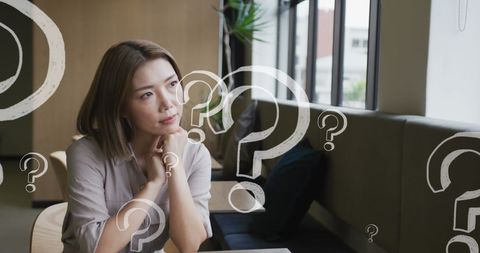 Thoughtful Businesswoman Surrounded by Question Marks