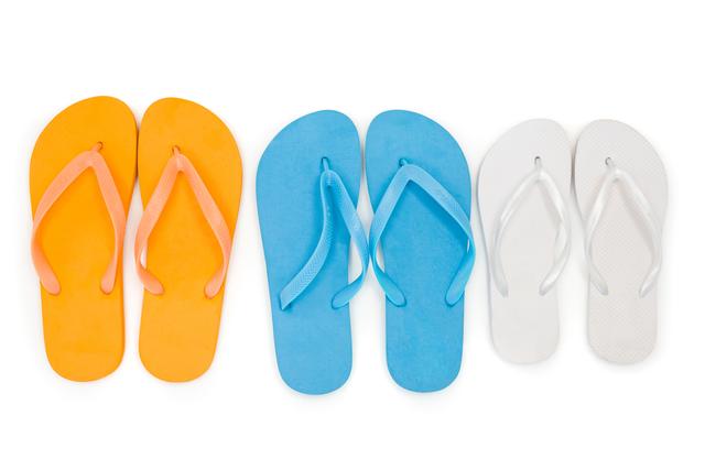 Three pairs of beach flip flop slippers and sunglasses on white background