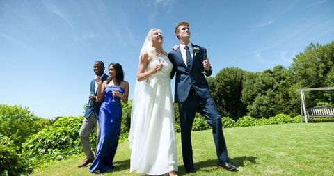 Joyful Wedding Couple with Witnesses Celebrating in Sunny Garden