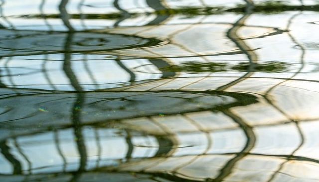 Rippling water reflecting distorted glass grid in soft light, abstract painterly patterns