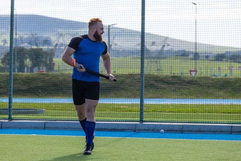 Athletic male player in action on field hockey turf