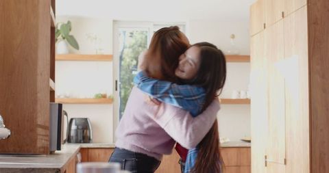 Mother embracing daughter in cozy home kitchen setting