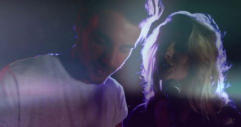 Energetic musical duo performing live with vibrant light effects