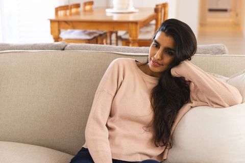 Asian Woman Relaxing on Beige Sofa in Minimalist Living Room