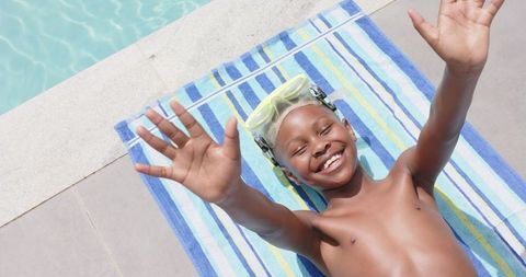 Smiling boy in swimming goggles waving by poolside