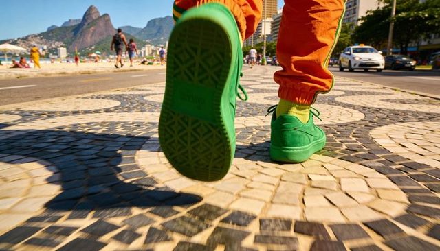 Walking green sneakers on mosaic beach promenade with neon socks and orange joggers