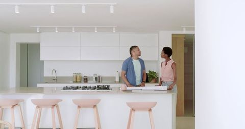 Couple Discussing Blueprint Plans in Modern White Kitchen