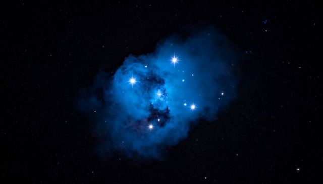 Cerulean nebula with spiked stars and dark dust lanes, luminous blue interstellar cloud