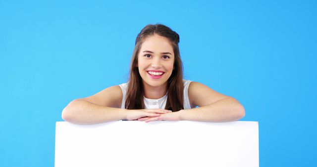 Smiling Young Woman Holding Blank Sign Against Blue Background - Download Free Stock Images Pikwizard.com