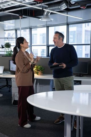 Collaborative conversation between diverse coworkers in modern open-plan office workspace