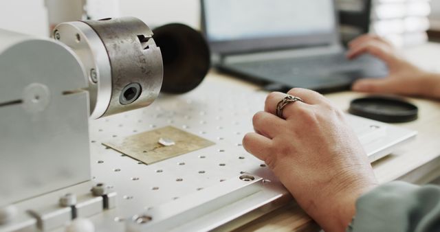 Engineer working on CNC milling machine at desk with laptop, suggesting advanced manufacturing technology application. Suitable for industrial, technology, and manufacturing contexts, emphasizing precision engineering and technological innovation.