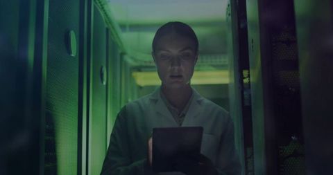 It technician analyzing data in dark server room