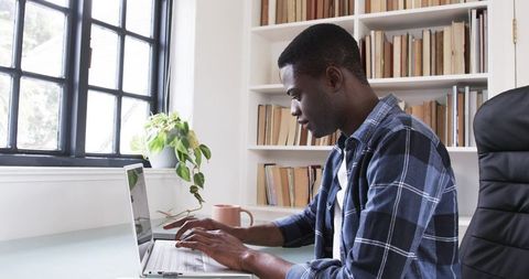 Focused Man Working on Laptop in Minimalistic Home Office