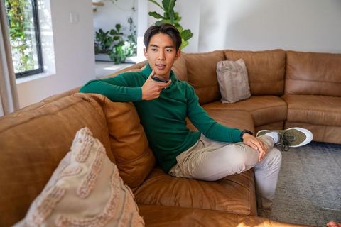Relaxing on brown leather sectional couch while using voice remote in modern living room