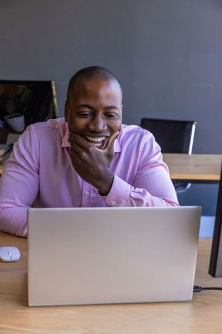 Smiling Professional Man Using Laptop in Modern Office
