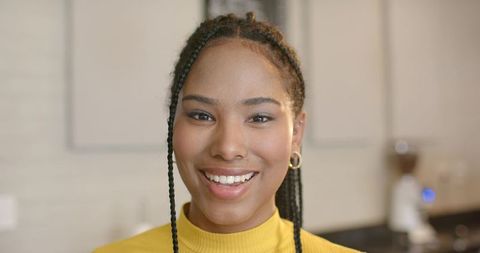 African american woman smiling in kitchen wearing yellow sweater and gold hoop earrings
