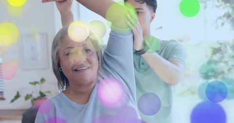 Caregiver helping senior woman with arm stretch home rehabilitation and physical therapy