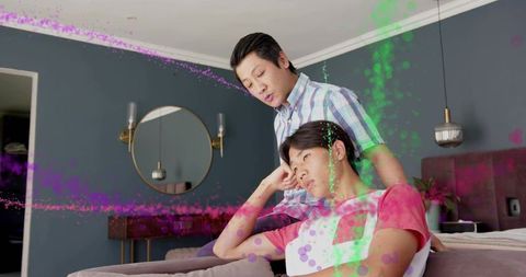 Father leaning over teen on couch having heartfelt conversation with colorful overlay