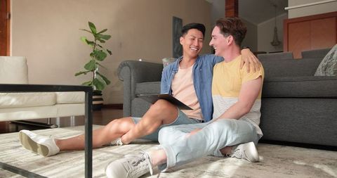 Smiling Diverse Male Couple Relaxing at Home with Tablet