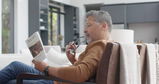 Middle-aged Man Reading Book on Cozy Living Room Chair - Download Free Stock Images Pikwizard.com
