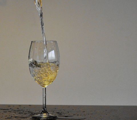Sparkling Water Pouring in Stem Glass on Minimalist Background