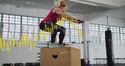 Woman balancing on plyo box with fitness data overlays in industrial gym