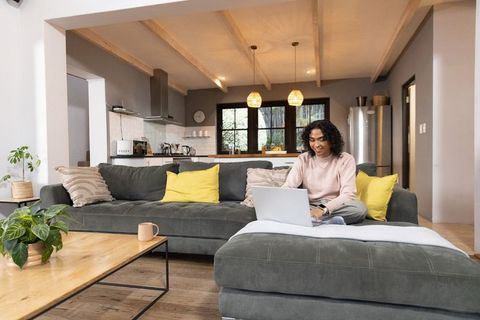 Non-binary adult working remotely on laptop in cozy modern open-plan living room