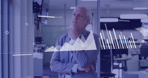 Mature businessman analyzing virtual financial data graphs in modern office