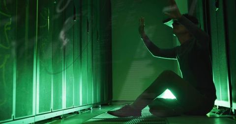 Technician wearing vr headset interacting with server racks in green-lit data center aisle